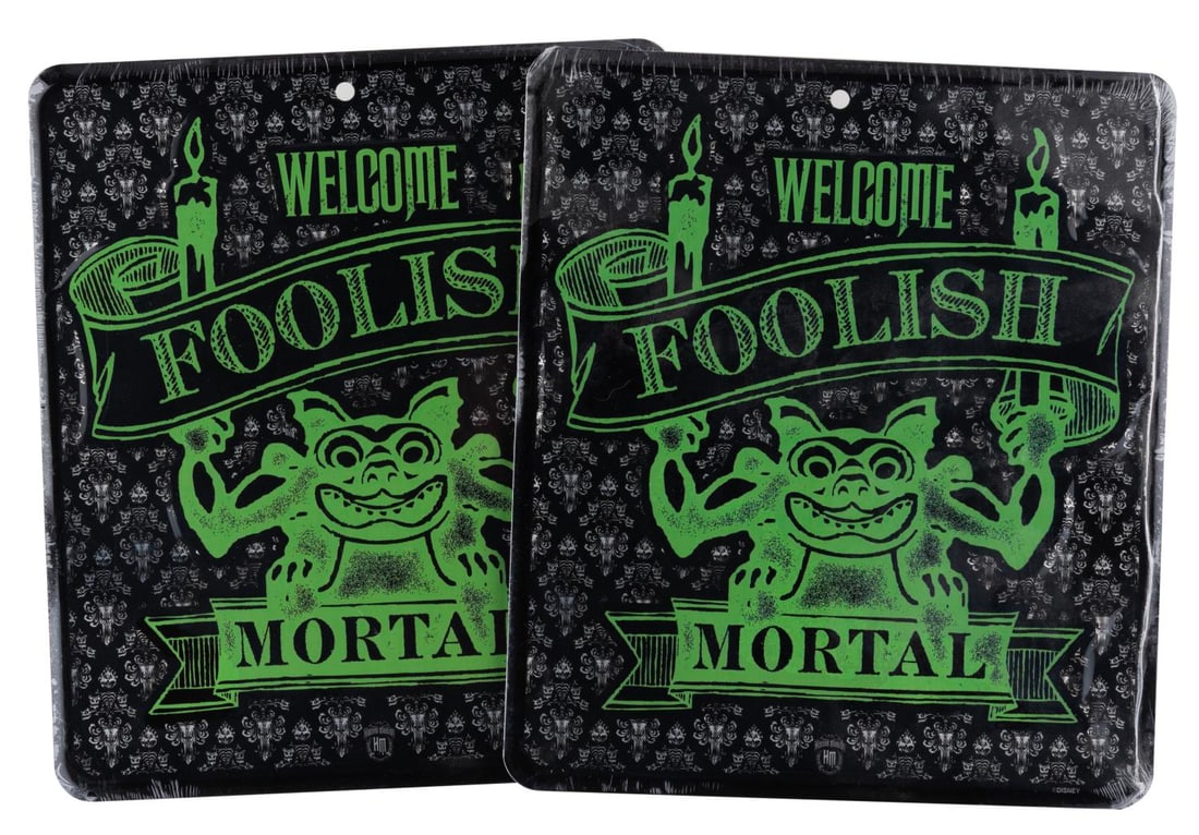 A Pair of Souvenir Haunted Mansion Tin Signs.: (Disneyland, 2010s) Two souvenir Welcome Foolish Mortal signs sold near the Haunted Mansion at Disneyland. Measuring 9.75" x 8.5", the signs are in fine condition sealed in original shrink wrap.