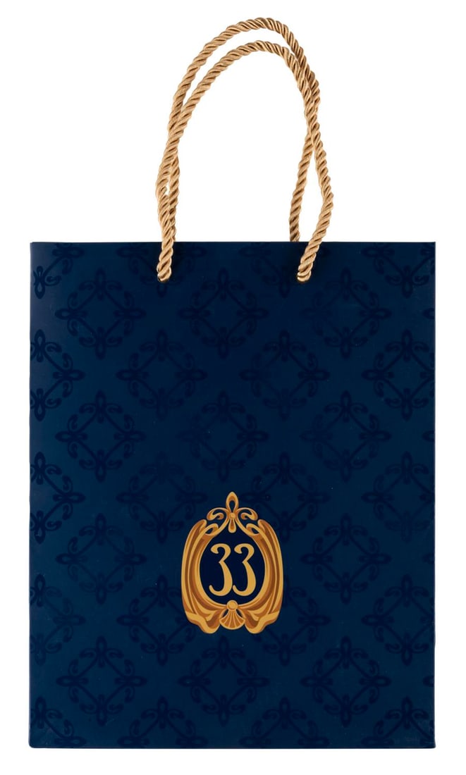 A Club 33 New Logo Shopping Bag.: (Disneyland, 2010s-20s) A Club 33 shopping bag featuring the Club's updated logo printed on the front and reverse. Included is a piece of Club 33 printed tissue paper wadded up inside. Measuring 4" x 