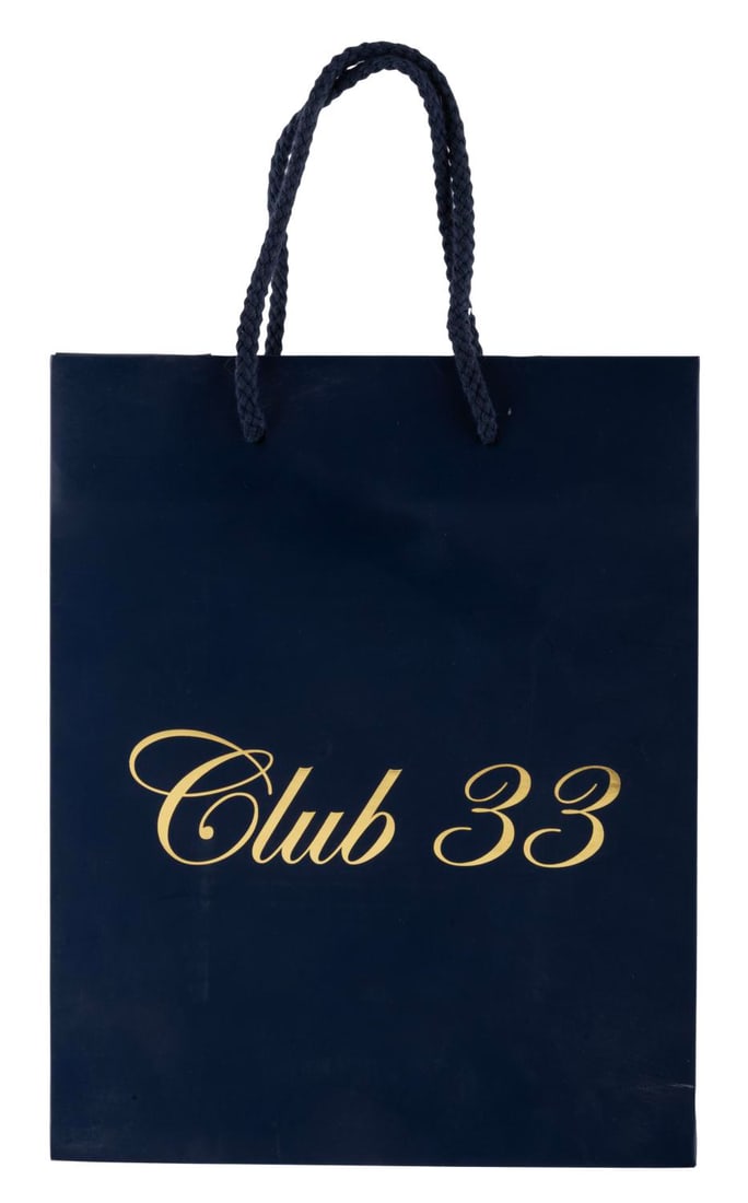 A Club 33 Shopping Bag.: (Disneyland, 2010s) A Club 33 shopping bag featuring "Club 33" printed in gold lettering on the front. Measuring 4" x 8" x 10" the bag is in good condition with light soiling, creasing, edge wear, and