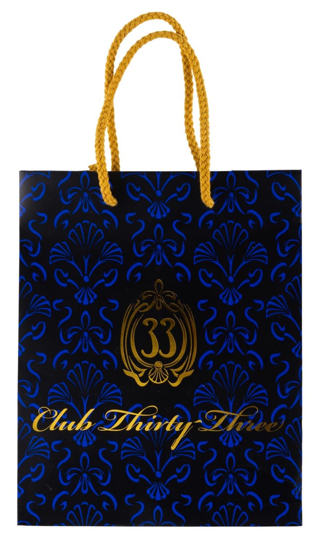 A Club 33 Patterned Shopping Bag.: (Disneyland, 2010s-20s) A Club 33 shopping bag featuring the updated logo printed in shiny gold lettering on both sides. Measuring 4" x 8" x 10", the bag is in good condition with creasing, soiling, a