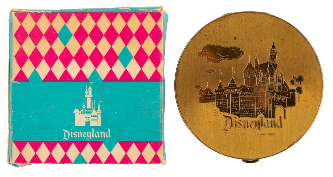 An Early Sleeping Beauty Castle Compact with Box.: (Disneyland, 1955) A circular Disneyland souvenir compact featuring a gold relief of Sleeping Beauty Castle, with the original box. Measuring 3.5" in diameter, the compact is in fair condition with