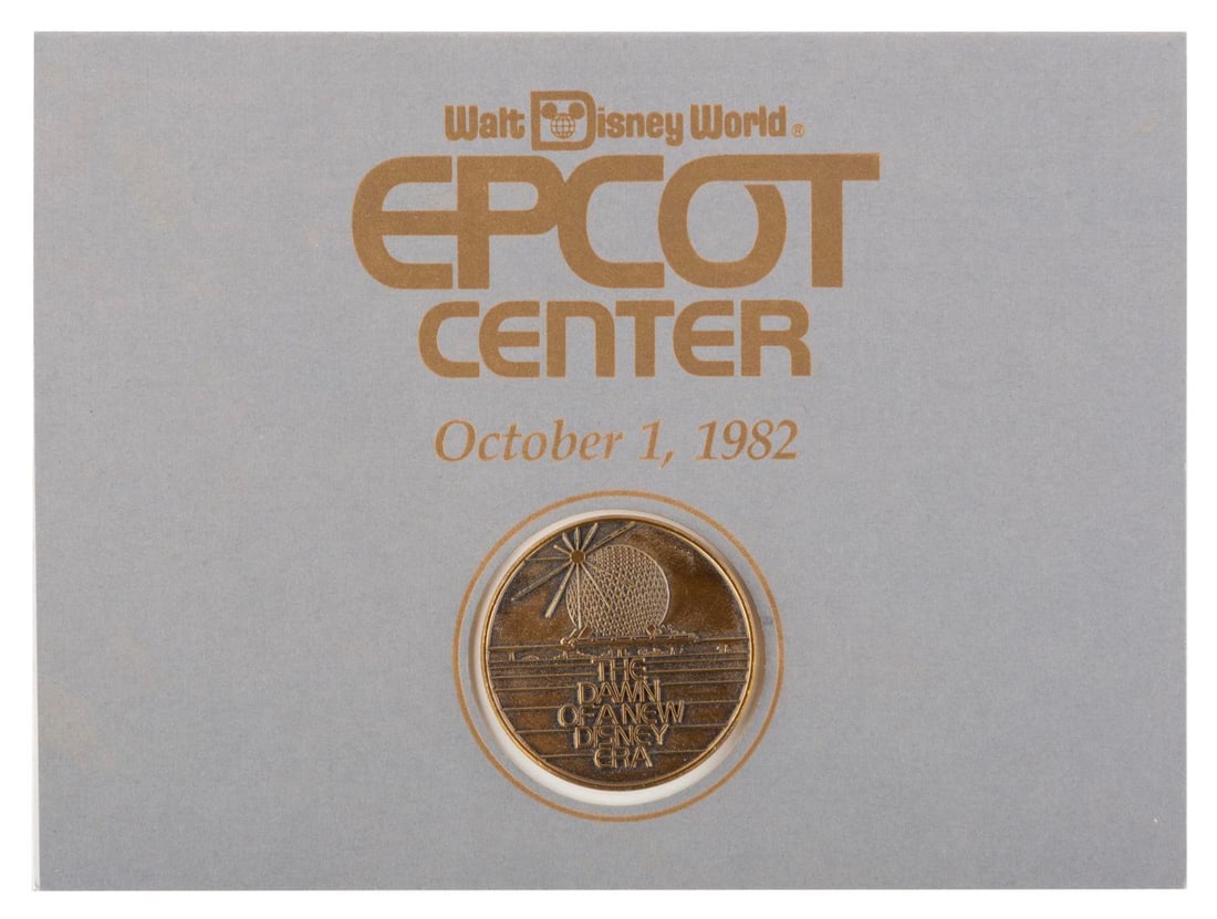 An EPCOT Center Opening Day Commemorative Coin.: (EPCOT, 1982) A medallion given to Walt Disney World employees to commemorate the Grand Opening of EPCOT Center on October 1, 1982. Measuring 1.75" in diameter on its 5" x 7" card, the coin is in