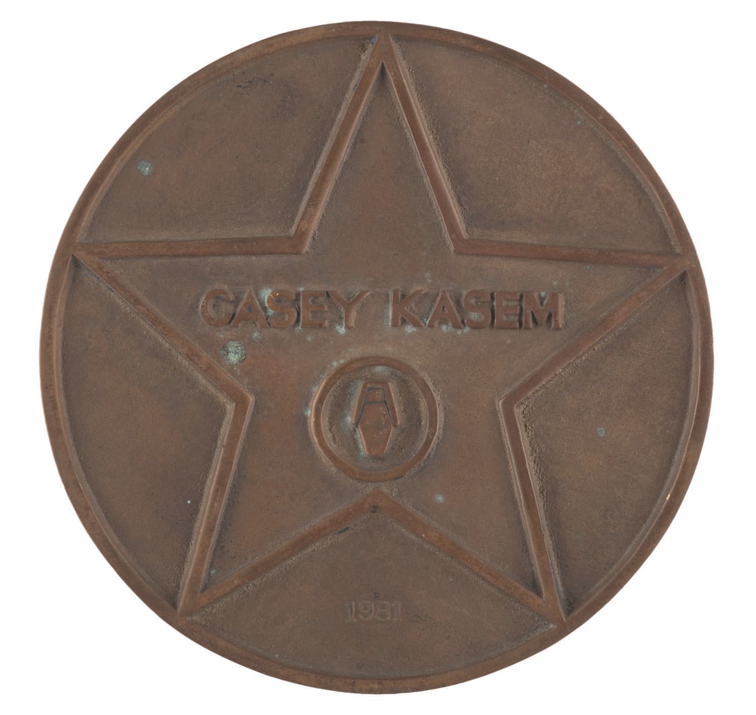 A Casey Kasem Hollywood Walk of Fame Plaque.: (Troosh, 1981) A bronze plaque made by artist Troosh Truchil for Casey Kasem, commemorating the "American Top 40" host's star on the Hollywood Walk of Fame. Measuring 5" in diameter and 0.5" thick,