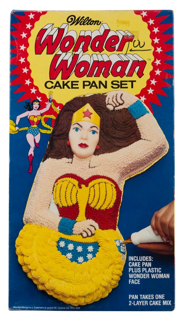 A Wonder Woman Cake Pan.: (Wilton, 1978) A Wonder Woman cake pan set, with instructions to frost the Amazing Amazon, and a plastic face to get the features perfect. Measuring 9" x 16" x 2", the aluminum cake pan is in fine unu