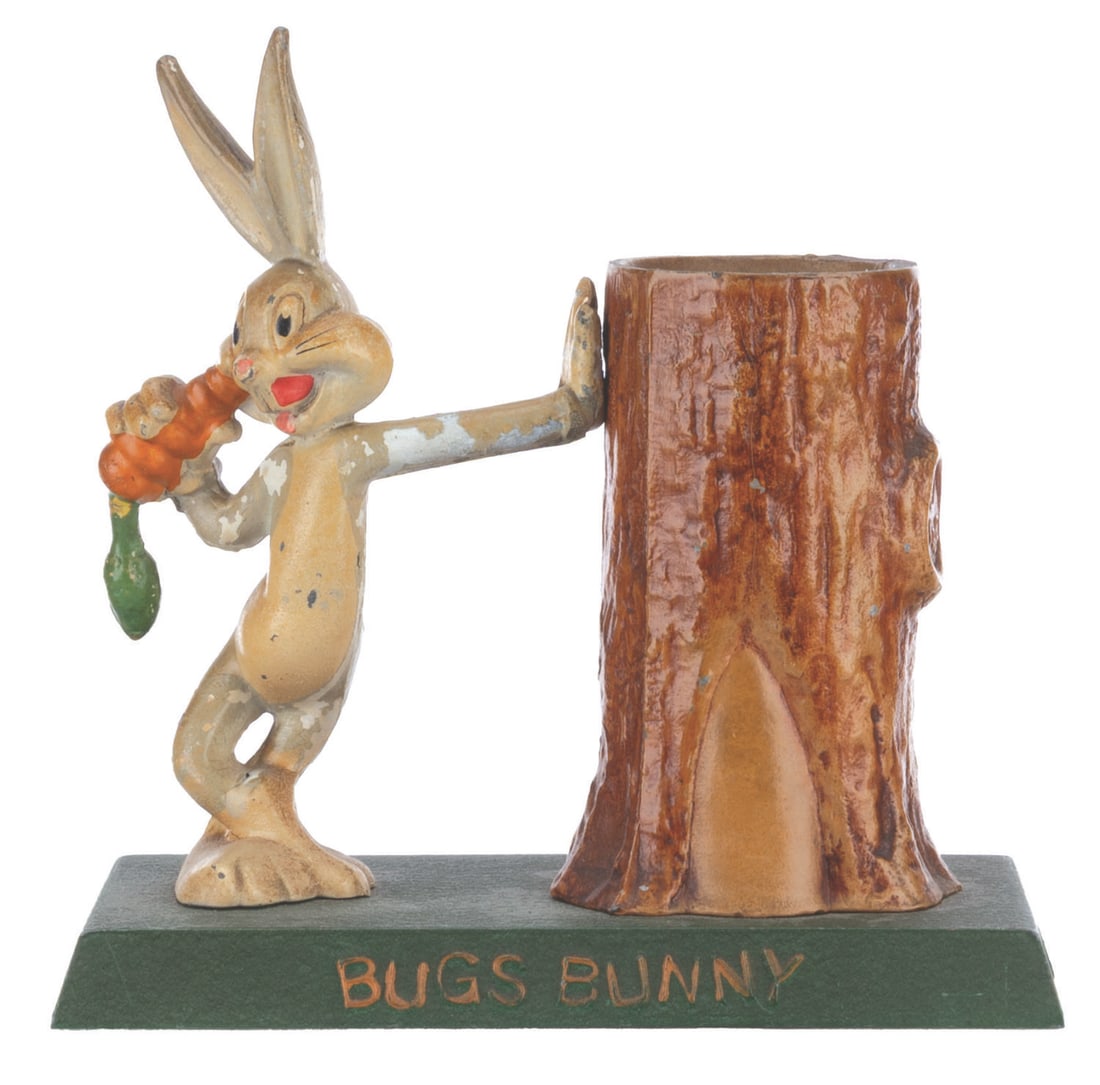 A Bugs Bunny Metal Coin Bank.: (Metal Moss MFG., 1940s-50s) A hand-painted cast-iron coin bank featuring Looney Tunes star Bugs Bunny. Bugs and the tree stump-shaped bank are attached to a base that can be opened to release the