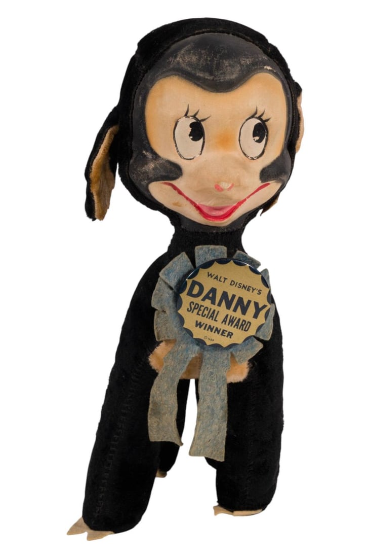 A "So Dear to My Heart" Danny Plush.: (Gund, 1940s-50s) A plush Danny the lamb from the live-action and animated "So Dear to My Heart." Danny has a molded plastic face and its original award button and ribbon. Gund became a Disney