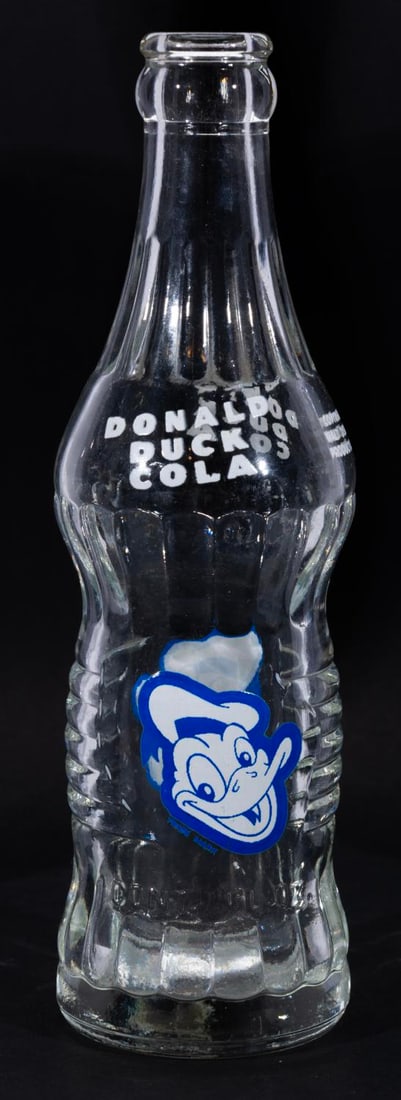 A Donald Duck Cola Bottle.: (General Beverages, 1952-55) A glass soda bottle from the popular Donald Duck beverages line of the 1950s. Measuring 9" tall and 2.25" in diameter, the bottle displays in fine condition.