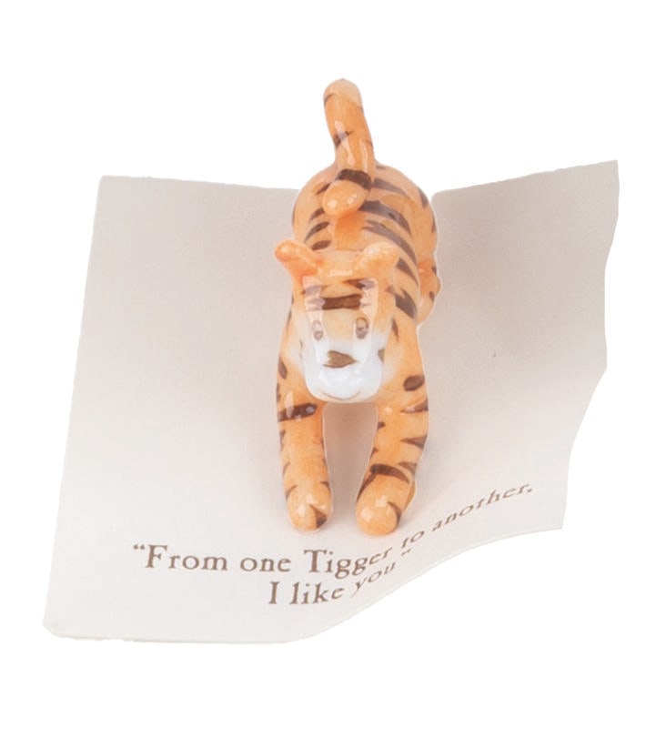 A Mini "Winnie the Pooh" Tigger Figurine.: (Michel and Co., 1990s) A mini ceramic figurine of Tigger, inspired by the original illustrations for the Winnie the Pooh books by E. H. Shepard. The figurine is attached to a card with a quote that