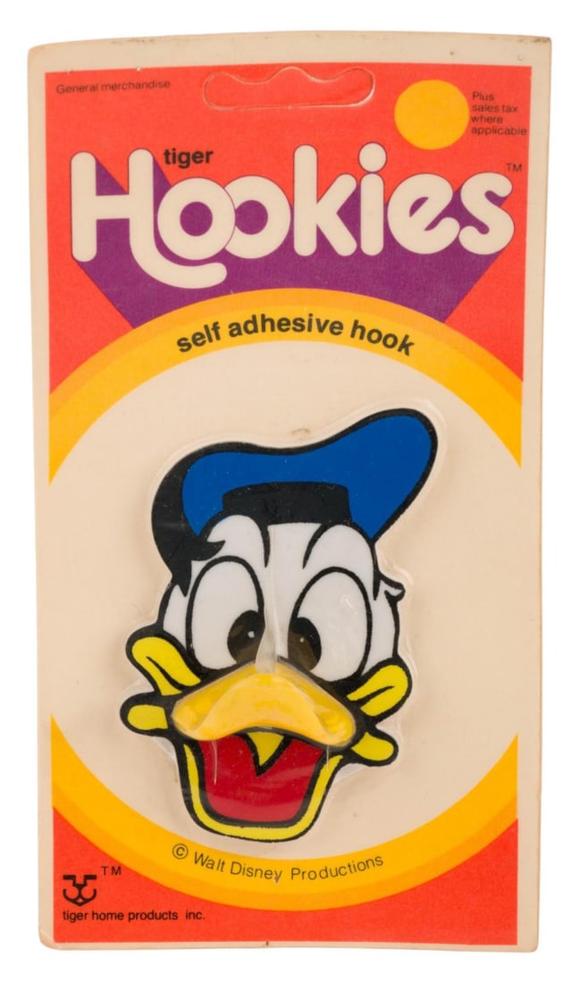 A Donald Duck Hookies Self Adhesive Hook.: (Tiger, 1977) A self adhesive hook shaped like Donald Duck, with his bill acting as the hook. Measuring 2.25" x 3" x 1.25" on the 3.5" x 6.5" card, the piece is in very good condition with slight
