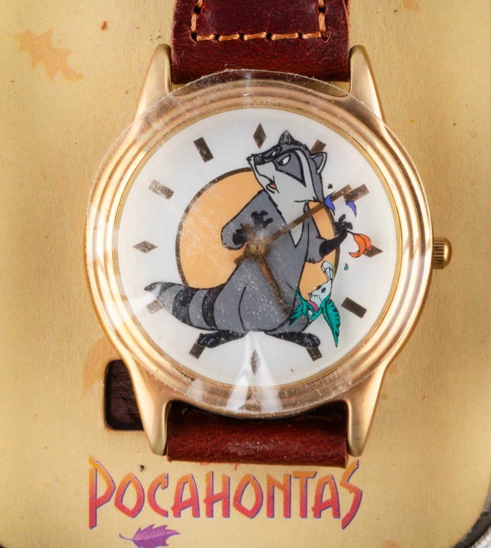 A "Pocahontas" Watch and Tin.: (Disney Store, 1995) A "Pocahontas" watch in its original tin. The face of the watch features Meeko, with Flik circling as the seconds feature. The watch and tin are in fine as-new condition,