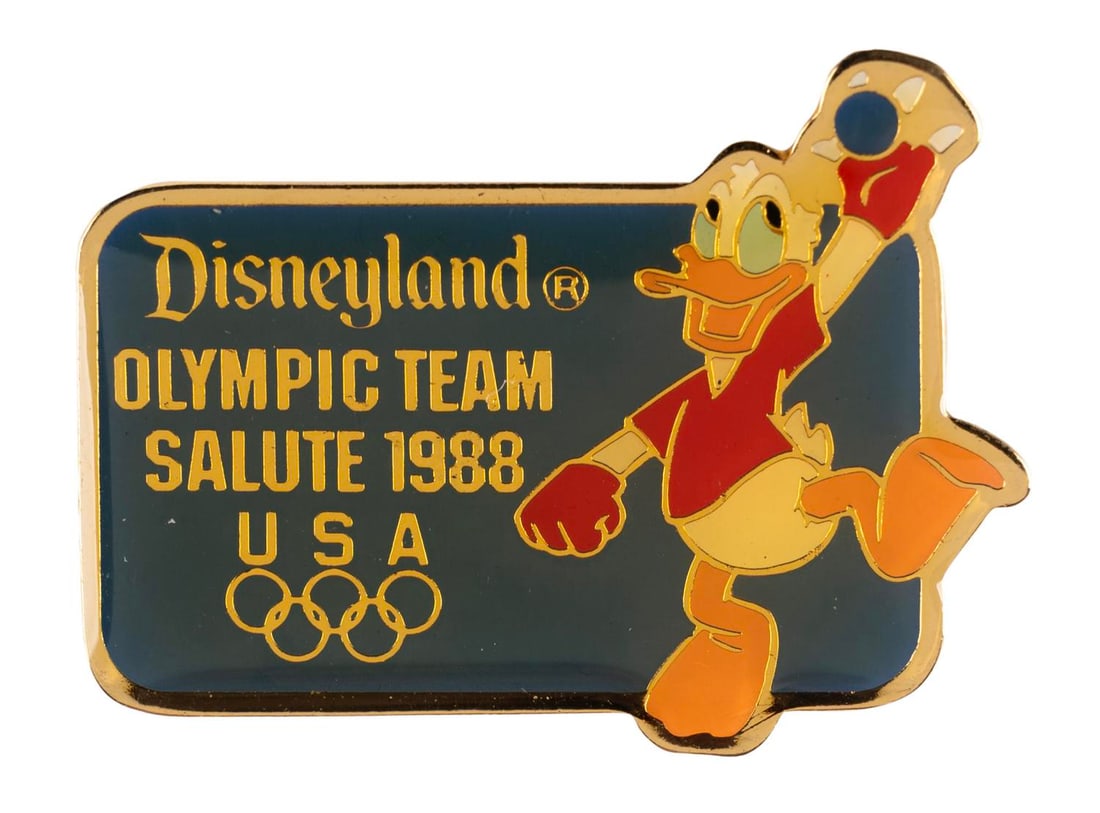 A Donald Duck Olympic Handball Pin.: (Disneyland, 1988) A Disneyland Olympic Team Salute 1988 pin featuring Donald Duck competing in handball. Measuring 1.25" wide, the pin is in very good condition with color shift from age.