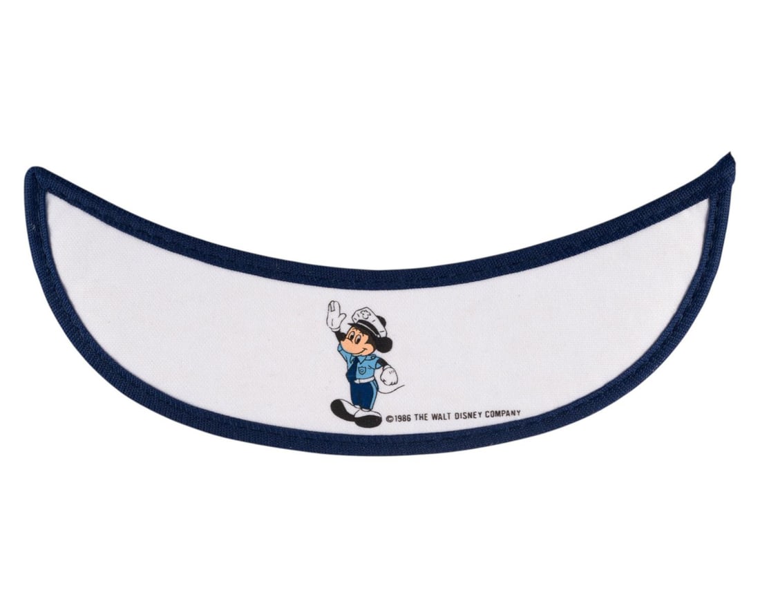 A Disneyland Security Uniform Sunglasses Visor.: (Disneyland, 1986) An original sunglasses visor for the Disneyland security uniform. Featuring an image of Mickey Mouse dressed as a security officer, the visor was created by Design Award in 1986.