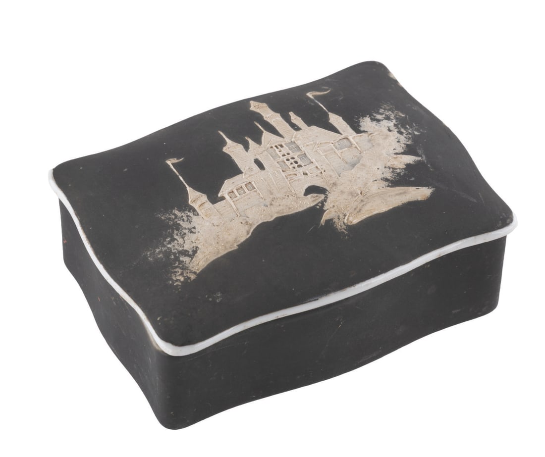 A Sleeping Beauty Castle Soapstone Trinket Box.: (Disneyland, 1960s) A black and white ceramic trinket box featuring a soapstone Sleeping Beauty Castle on the lid. The trinket box was created in a very unusual color choice for the Park, and