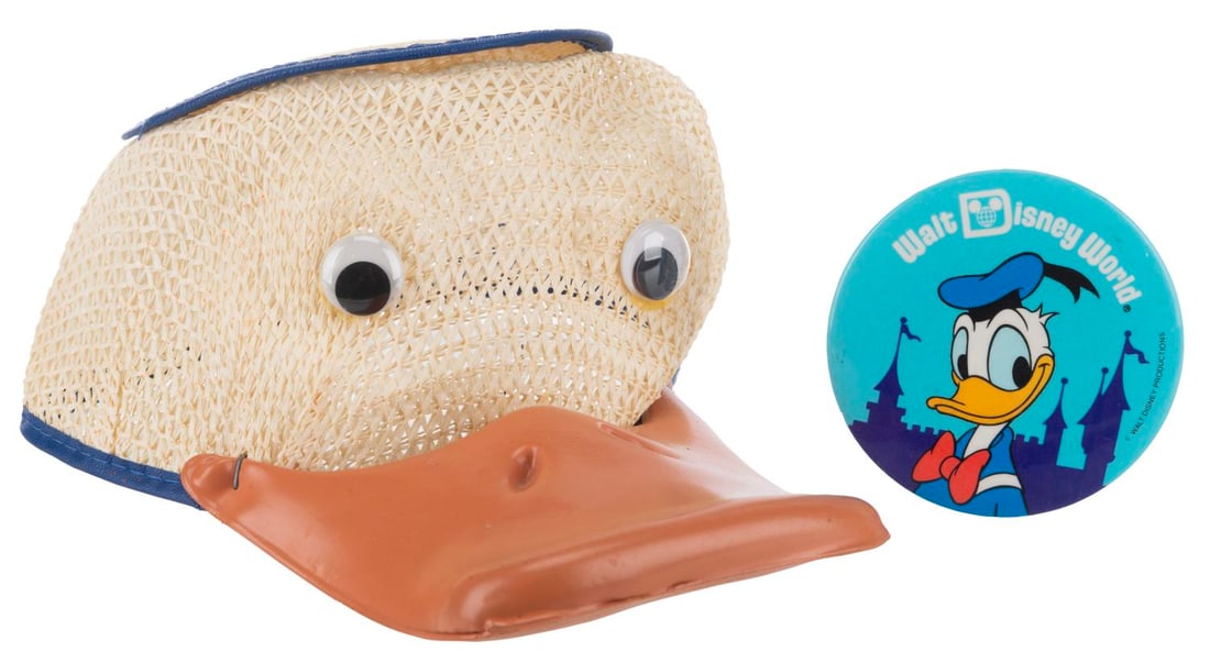 A Donald Duck Squeaker Hat and Button.: (Walt Disney World,1970s-80s) A Donald Duck souvenir squeaker hat and pinback button. The hat is labeled a size small, and the button measures 3" in diameter, both in good condition with scratches,