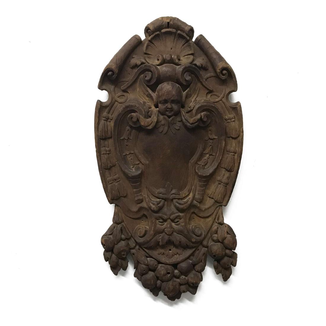 French Rococo Carved Plaque Ornamental Plaque: A French Rococo period heavily hand carved architectural ornamental plaque. Among the deep scrolls a beautiful young cherub appears in great detail with carved hair and joy filled cheeks. Over i
