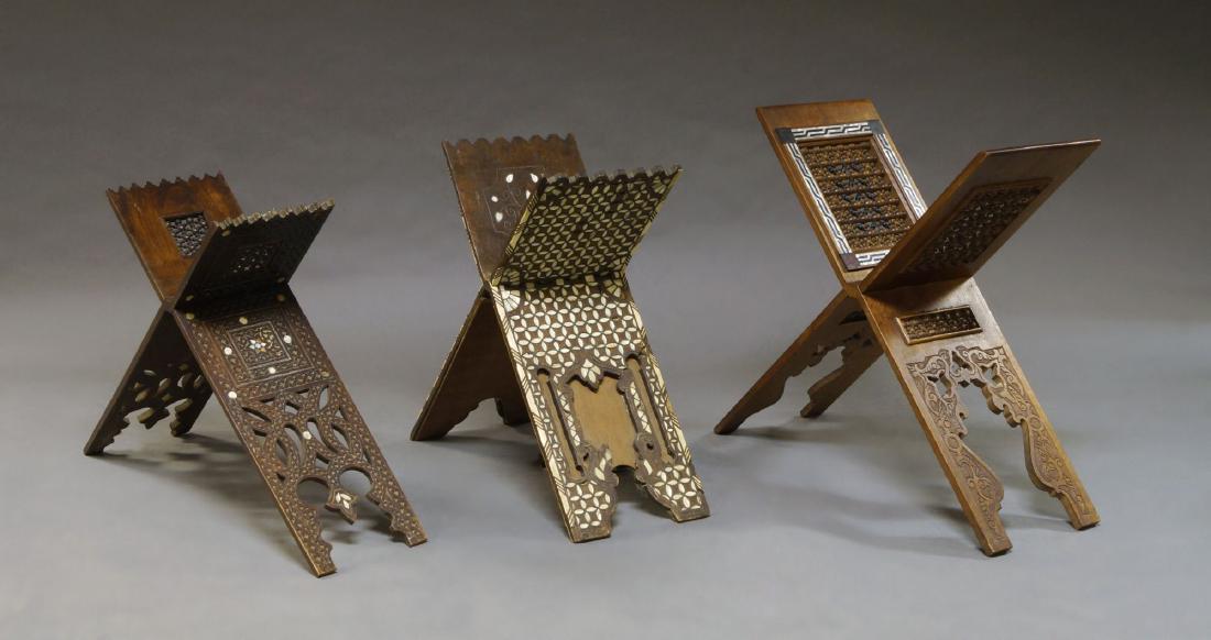 Three wooden qur'an stands, Syria, late 19th-20th: Three wooden qur'an stands, Syria, late 19th-20th century, one with mother-of-pearl and white metal inlay, together with two inset with mashribiyya work panels, largest 33 x 25cm, (3)