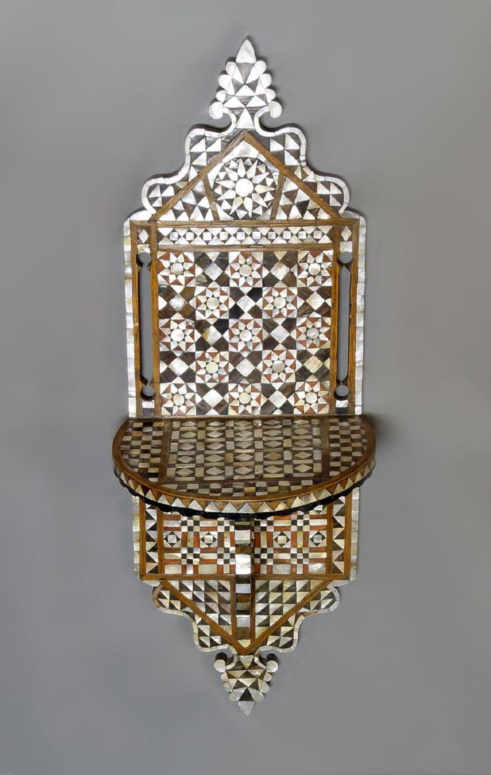 A mother of pearl inlaid turban stand, kavukluk, Syria,: A mother of pearl inlaid turban stand, kavukluk, Syria, early 20th century, with shaped and pierced back, geometrically inlaid with eight point stars, with semi-circular plateau, on scrolling support,