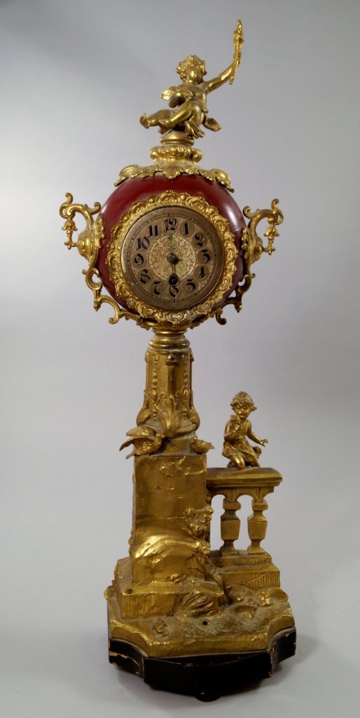 A large Continental gilt metal mantle clock, late 19th: A large Continental gilt metal mantle clock, late 19th century, the circular dial enclosed within foliate motif, surmounted by seated putti, raised on garden scene with child and doves on a wall, rais
