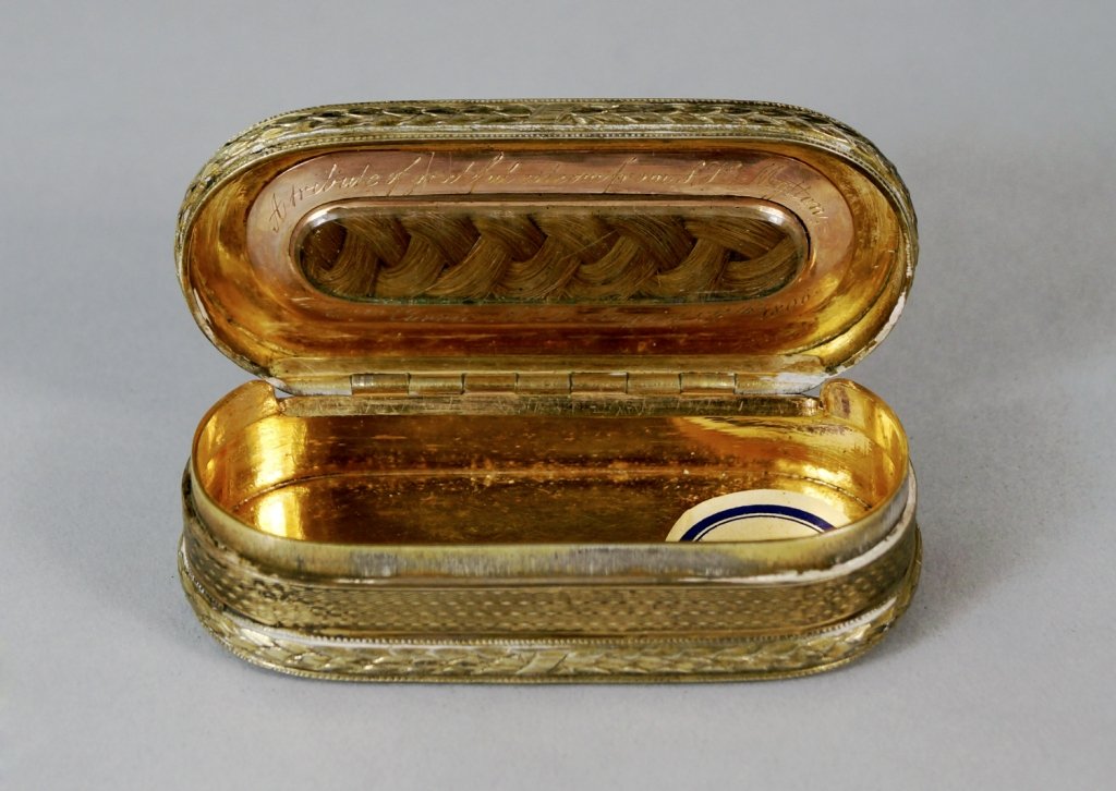 A George III silver gilt memorium snuff box, London: A George III silver gilt memorium snuff box, London c.1806, by Alexander J. Strachan, with cast rococo shell and foliage border, laurel and ribbon bands and engine turned panels, the cover interior fi