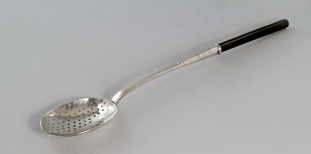 A large Charles II silver sieving spoon, c.1693,: A large Charles II silver sieving spoon, c.1693, maker's mark RL above fleur de lys, within a shield, the spoon stem with chased armorial and inset wooden handle, approx 49cm long. Note: The armorial 