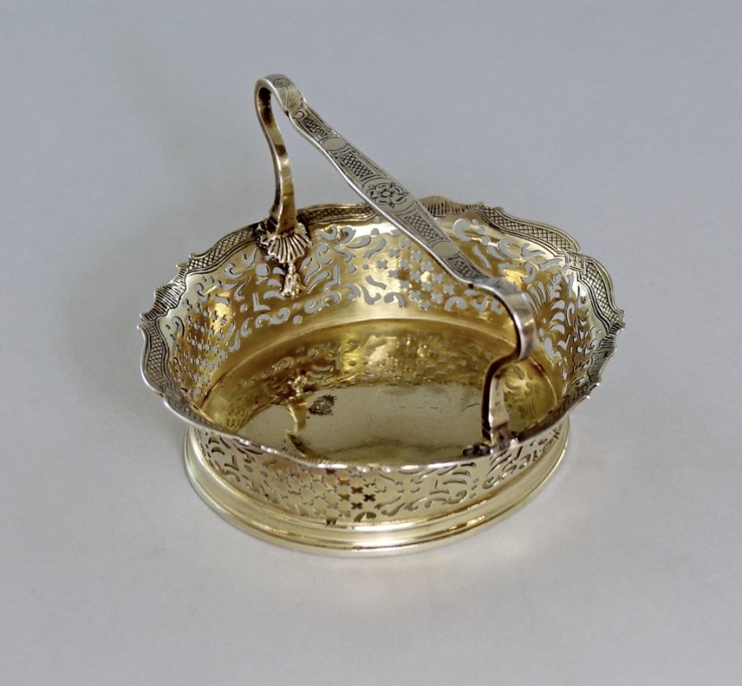 A George II silver gilt pierced basket, London c.1736,: A George II silver gilt pierced basket, London c.1736, maker AV with pellet above, possibly Aymé Videau, the raised pierced sides with flared and chased scalloped rim, the shaped and chased handle te