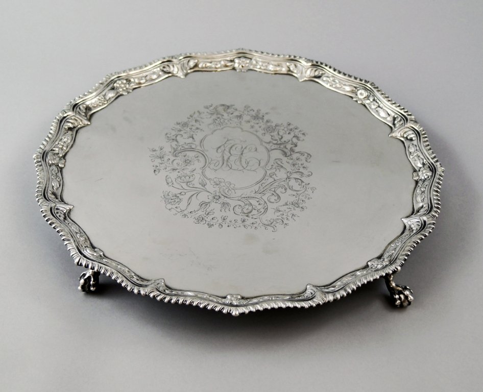 A George III silver salver, London c.1768, by Richard: A George III silver salver, London c.1768, by Richard Rugg I, with pie crust and floral chased border and central engraved floral cartouche and initials, raised on four ball and claw feet, approx 38cm