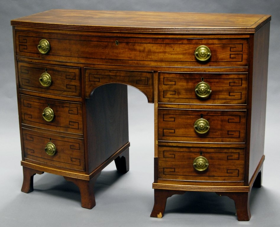 A mahogany bowfront kneehole desk, with a reeded top: A mahogany bowfront kneehole desk, with a reeded top edge, above a long drawer and six short ebony strung drawers, raised on bracket feet, elements 19th century, 91 cm high x 121 cm wide x 57 cm deep.
