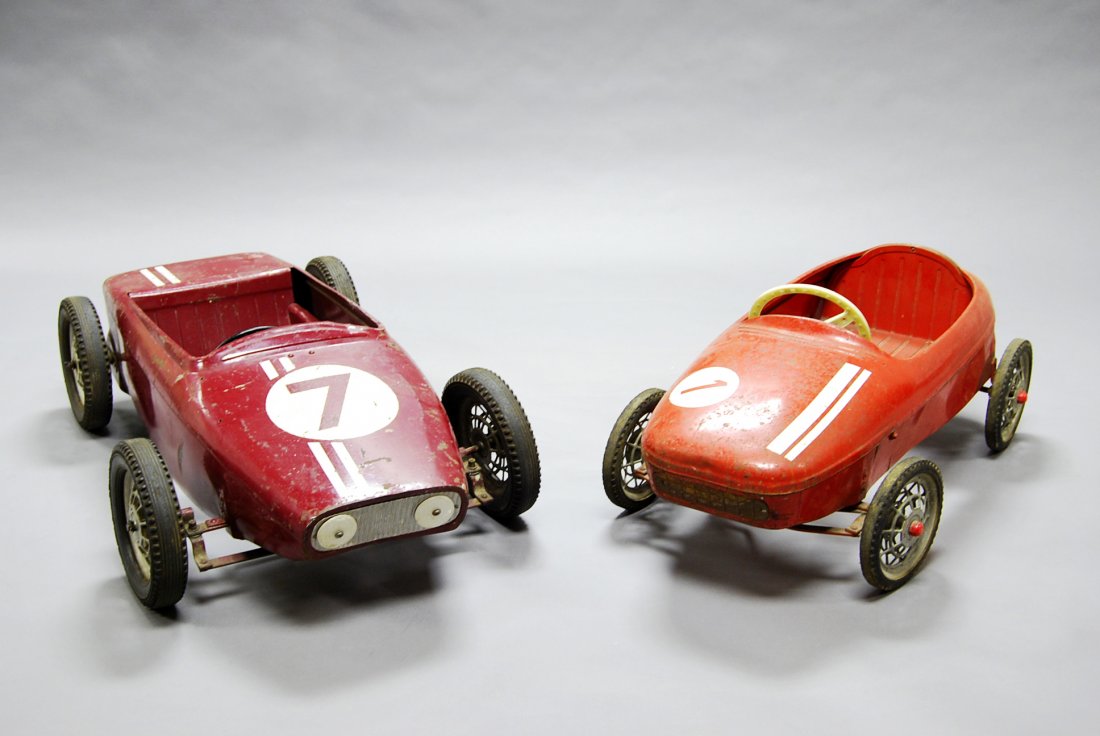 An English Lotus F1 children's pedal car, in maroon: An English Lotus F1 children's pedal car, in maroon livery, No. 7, circa. 1960, with steering wheel and pedal mechanism, 99cm. x 48cm., together with another racing car, in red livery, No. 1, with ste