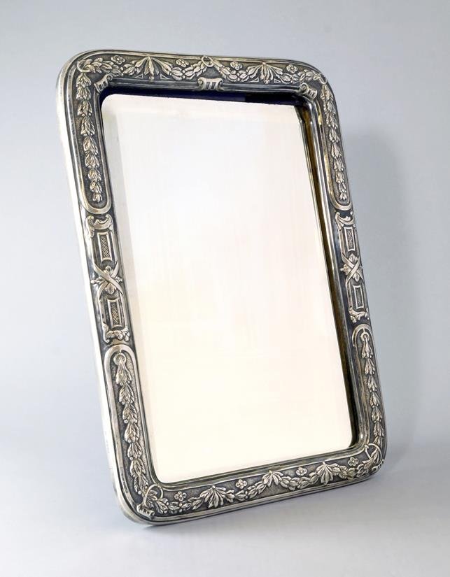 A silver framed mirror, London c.1878, William: A silver framed mirror, London c.1878, William Frederick Williams, the cast cushion frame of curved rectangular form with Neo-Classical foliate swags to top and bottom and ribbon tied panels to either