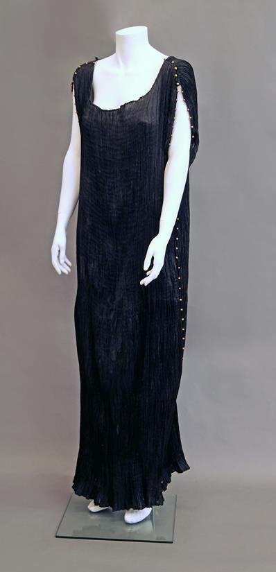 A Mariano Fortuny Delphos tea gown, c.1920s, the: A Mariano Fortuny Delphos tea gown, c.1920s, the sleeveless pleated black silk gown with Venetian glass bead decoration to shoulders and side seams.