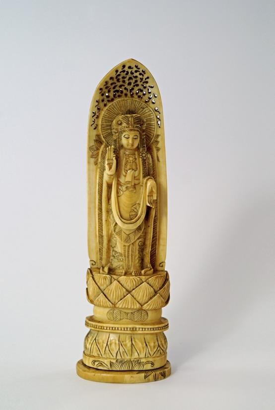 A Japanese ivory model of a Buddhist priest standing on: A Japanese ivory model of a Buddhist priest standing on a lotus pod, late 19th/early 20th century, 21.5cm. high