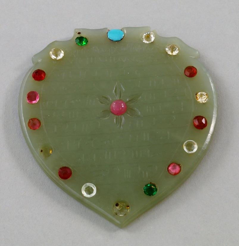 A Mughal carved celadon jade calligraphic plaque, of: A Mughal carved celadon jade calligraphic plaque, of leaf form, decorated with central flower surrounded by lines of script, to verso highly polished, with later applied cabochons, 7.5cm high x 6.75cm