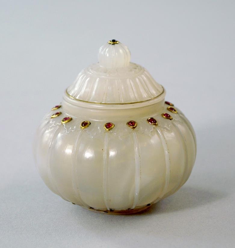 A Mughal jade spherical jar and cover, with reeded: A Mughal jade spherical jar and cover, with reeded body, applied with red glass cabouchons, 7cm. high