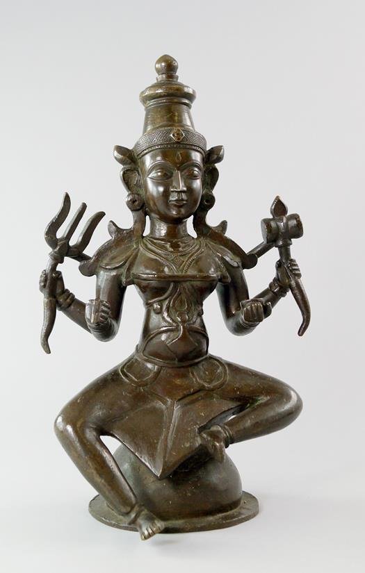 A bronze model of a seated god, his multiple arms: A bronze model of a seated god, his multiple arms holding precious weapons and precious objects, modelled seated in a spherical dias, 38cm. high