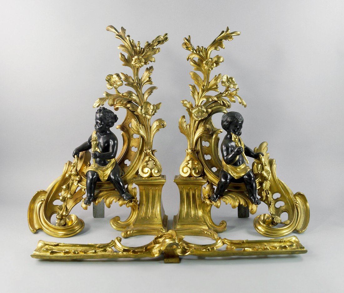 A pair of French bronze and patinated bronze andiron,: A pair of French bronze and patinated bronze andiron, late 19th century, formed of a large scrolling acanthus leaf, with flowering ends, mounted with male and female child figures, classically draped 