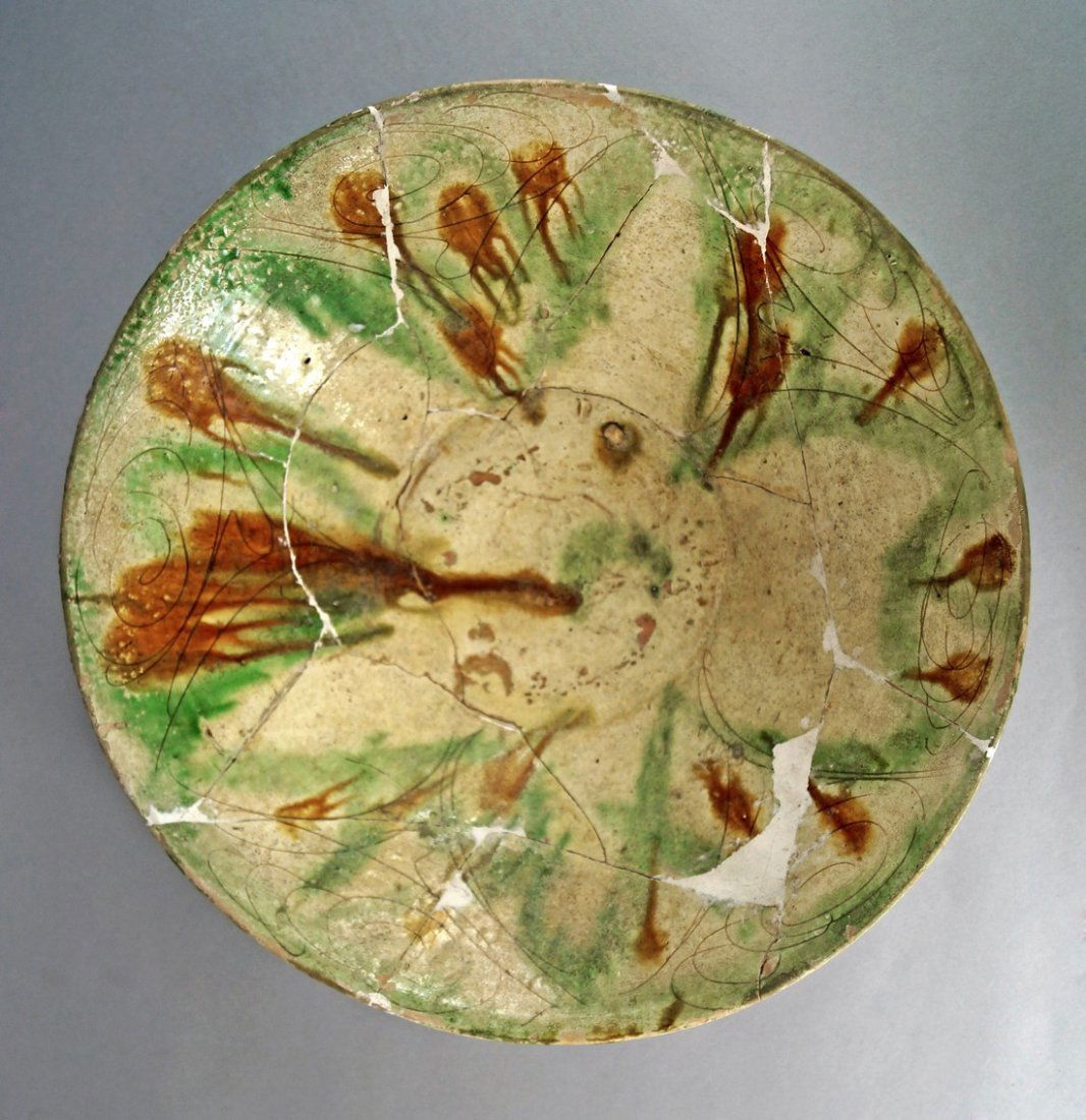 A Nishapur sgraffito splashware pottery bowl, 10th: A Nishapur sgraffito splashware pottery bowl, 10th Century, the earthenware body incised with spiral and linear motifs radiating from the centre, decorated with splashes of green, brown and aubergine
