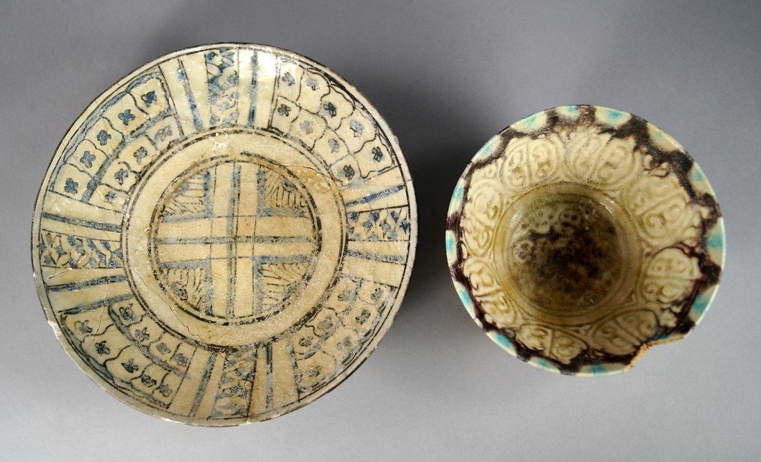 A Persian blue brown glazed pottery bowl, 9th/11th: A Persian blue brown glazed pottery bowl, 9th/11th Century, central cross design enclosed by continuous panels of flower heads within brown line borders, 24cm diam, with another smaller bowl, (2)