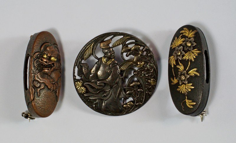 A Japanese Shakudo brooch, of pierced circular form,: A Japanese Shakudo brooch, of pierced circular form, depicting a man in traditional costume in a garden setting, approx 3.4cm diameter, together with two further Shakudo brooches, of oval form, approx