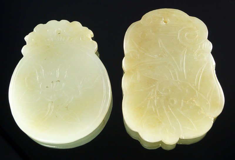 A Chinese carved pale green jade plaque, of oval form: A Chinese carved pale green jade plaque, of oval form with surmount, decorated with foliage on one side and geometric motifs to other, 5.5cm high, with another Chinese carved jade plaque, (2)