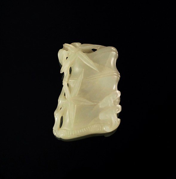 A Chinese carved pale green jade plaque, decorated with: A Chinese carved pale green jade plaque, decorated with lotus and leaves, 6cm wide