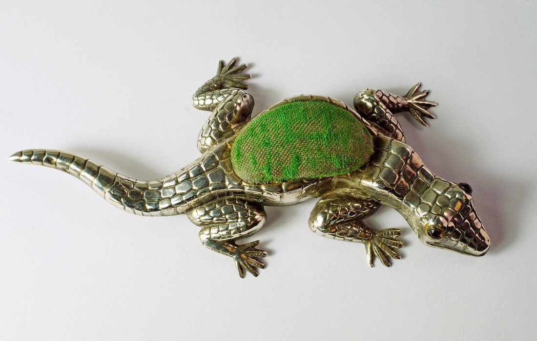 A silver novelty pin cushion, Birmingham c.1907,: A silver novelty pin cushion, Birmingham c.1907, Crisford & Norris Ltd, in the form of a crocodile, with glass eyes, 11cm. approx