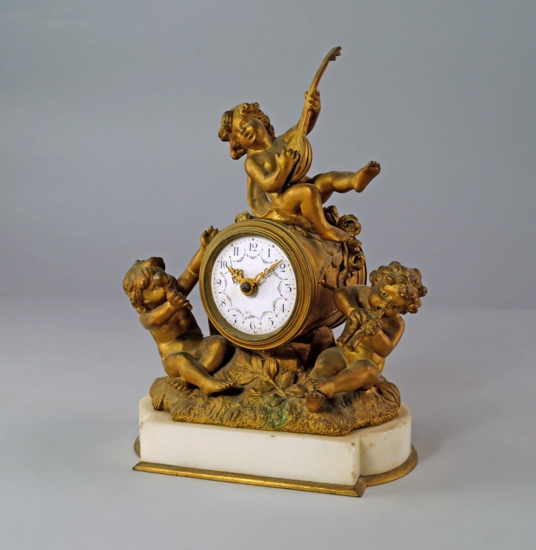 A French ormolu and white marble clock, 19th century,: A French ormolu and white marble clock, 19th century, the case mounted with figures playing instruments, the white enamel dial with Arabic numeral chapter ring decorated with floral swags, with barrel