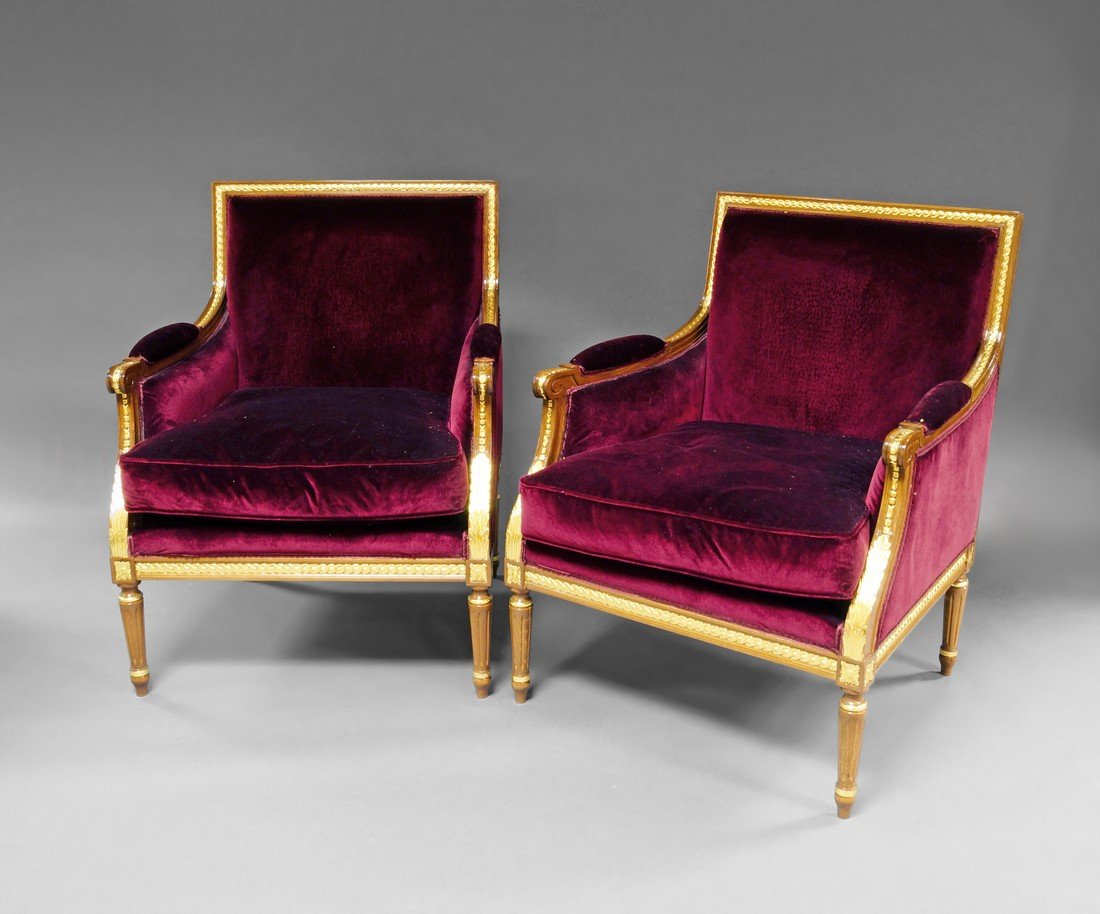 A pair of Louis XVI style beech giltwood arm chairs,: A pair of Louis XVI style beech giltwood arm chairs, with rectangular backs, applied scroll decoration, with red velvet over stuff seats and cushion, on fluted tapering legs, (2).