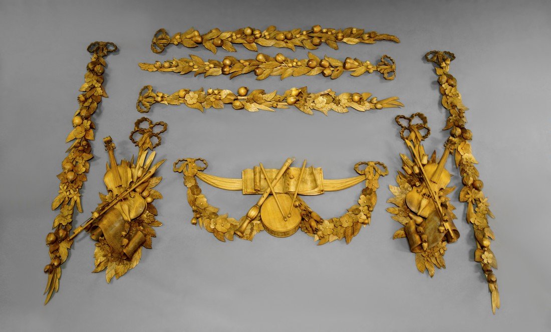 A group of carved wood wall appliques in the manner of: A group of carved wood wall appliques in the manner of Grinling Gibbons, carved in relief with swags of fruit and flowers and groups of instruments, consisting of five straight sections and three swag