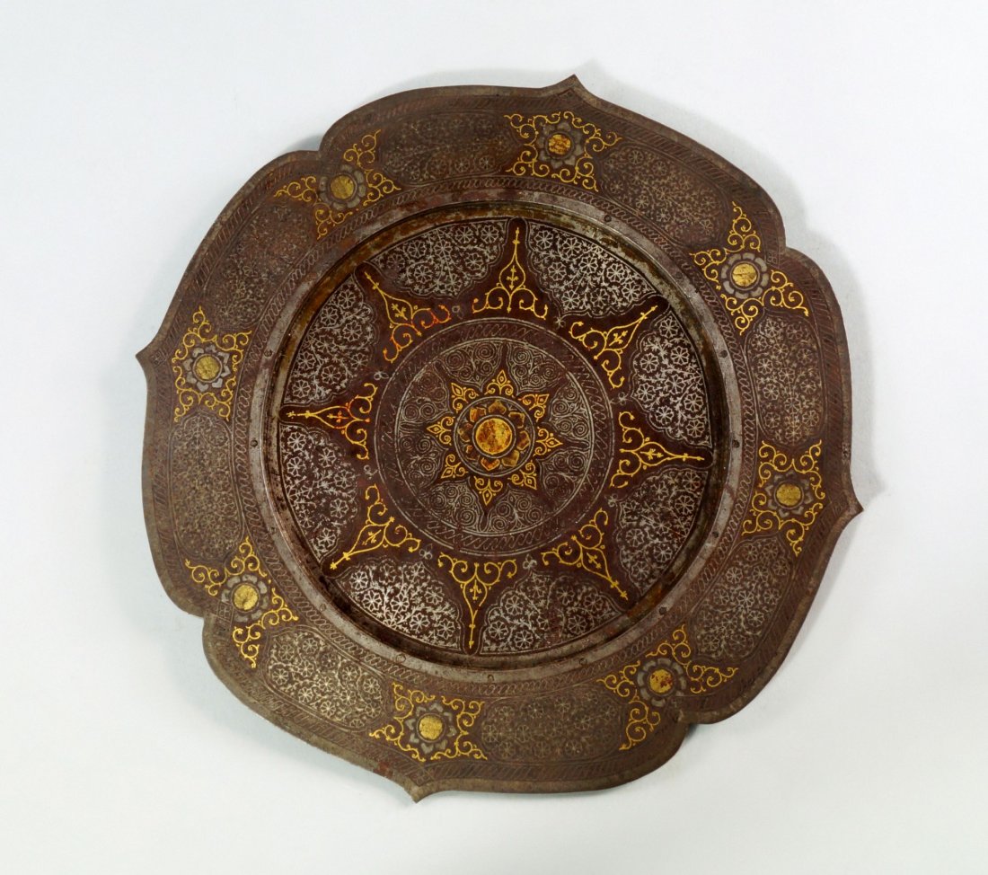 A Mughal steel damascened plate, 19th century, of ogee: A Mughal steel damascened plate, 19th century, of ogee arch form to the rim, inlaid with silver and gold stylised tendrils and flower heads, 23.5cm diameter
