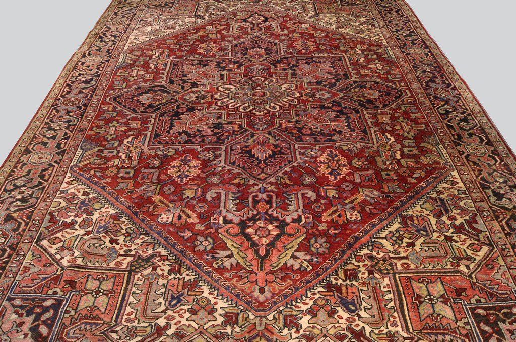 A Heriz carpet with indigo and ivory pole medallion in: A Heriz carpet with indigo and ivory pole medallion in a deep red field, with ivory spandrels and a charcoal main border 386 x 280 cm