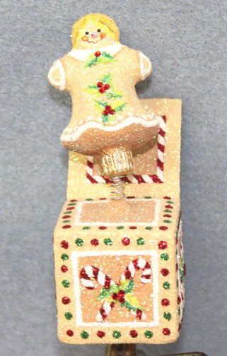Patricia Breen "Jolly Suprise-Gingergirl" Ornament: Patricia Breen "Jolly Suprise Gingergil" Christmas ornament. Coffee colored gingerbread girl popping out of a jack-in-the-box. The box trimmed in candy canes and colored crystals on a clip. Stand not