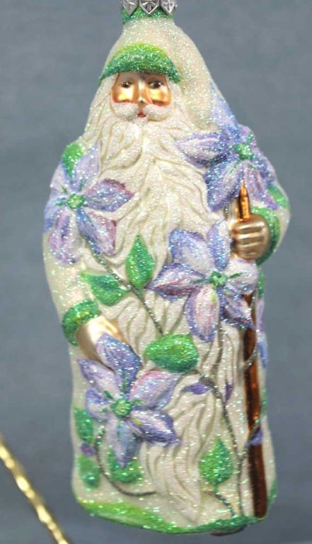 Patricia Breen "Clematis Santa" Ornament: Patricia Breen "Clematis Santa" Christmas ornament. Fully glittered pearlized version of Santa holding a copper-brown staff with shaded blue clematis flowers and green vine foliage intertwined around 