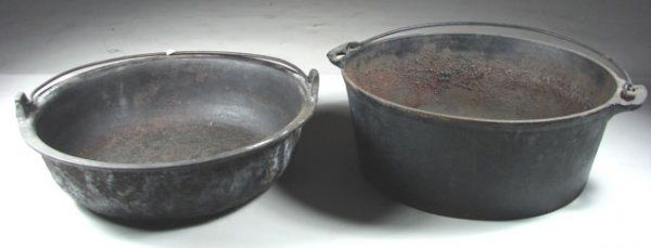 Two Early Sand Cast Cooking Pans: Both of these pans are unmarked but have nice sand cast lines on the bottom. Both have wire bale handles for hanging over the fire. Shallow pan has a crack along one side. The deeper pan is fine. The