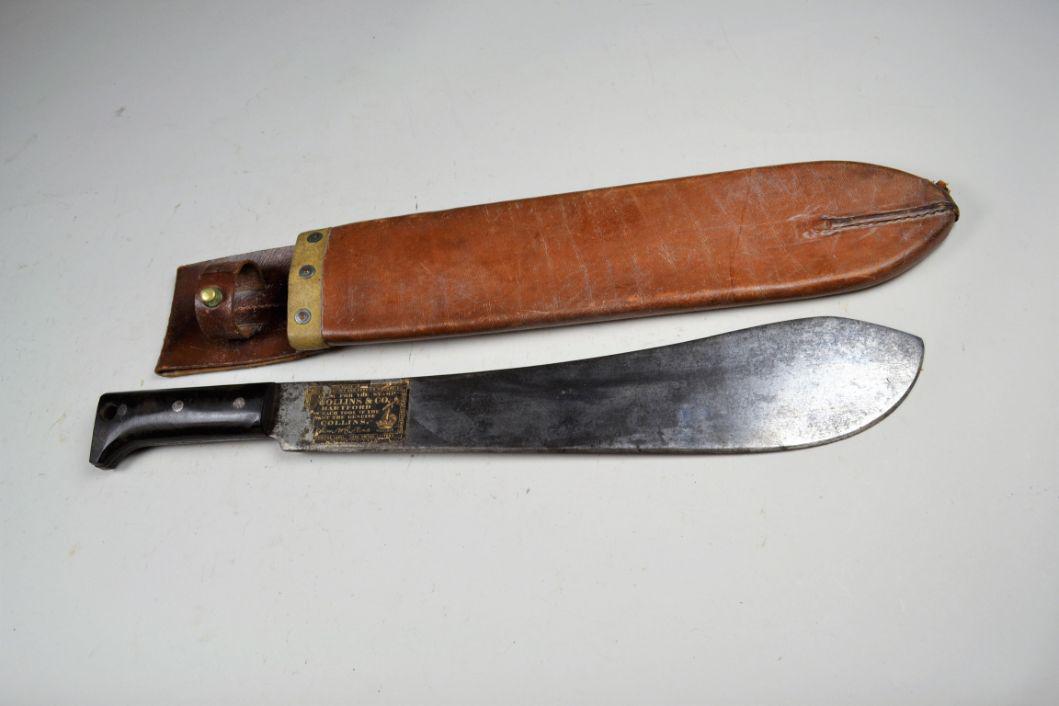 Collins Legitimus No 1250 Machete Dated 1945: in Robco LTD Montreal 1945 scabbard. Blade still has 90% of the original paper label. Grey blade with moderate pitting. Scabbard is very good with moderate wear. Blade 14 1/2", overall 19 1/2"